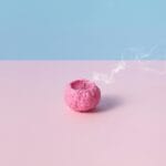 Różowa świeca w kształcie mózgu dymiąca na pastelowym tle