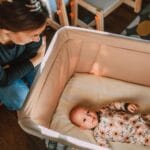 Mama z czułością spogląda na niemowlę leżące w łóżeczku