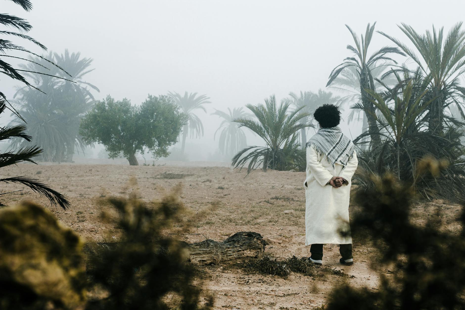 Mężczyzna w tradycyjnym stroju wśród mglistych palm w Tunezji