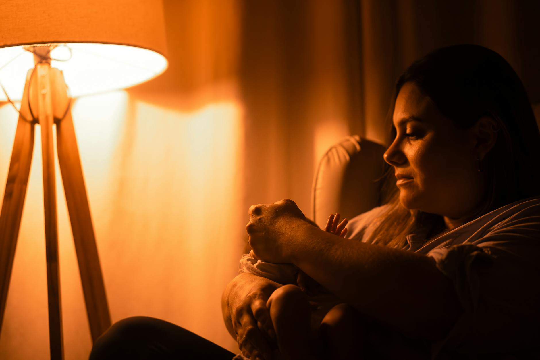 Mama tuląca niemowlę w ciepłym świetle nocnej lampki Mama tuląca niemowlę w ciepłym świetle nocnej lampki