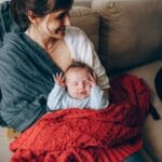 Mama trzyma śpiące niemowlę owinięte w koc w sypialni